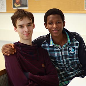 Kaksi nuorta miestä katsovat hymyillen kameraan.