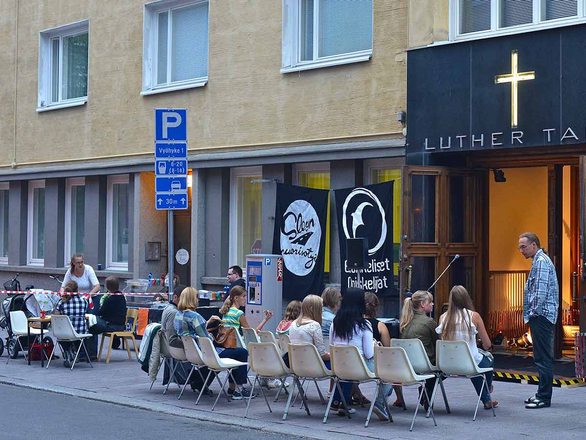 Kuvassa on ihmisiä Luther-talon pihalla ja pastori Lasse keskustelee ihmisten kanssa